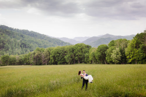 Groom carries Bride in tall grasses elopement 