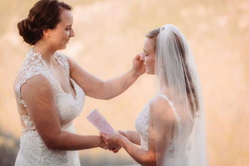 LGBTQ Wedding Ceremony Bride wipes tears of partner