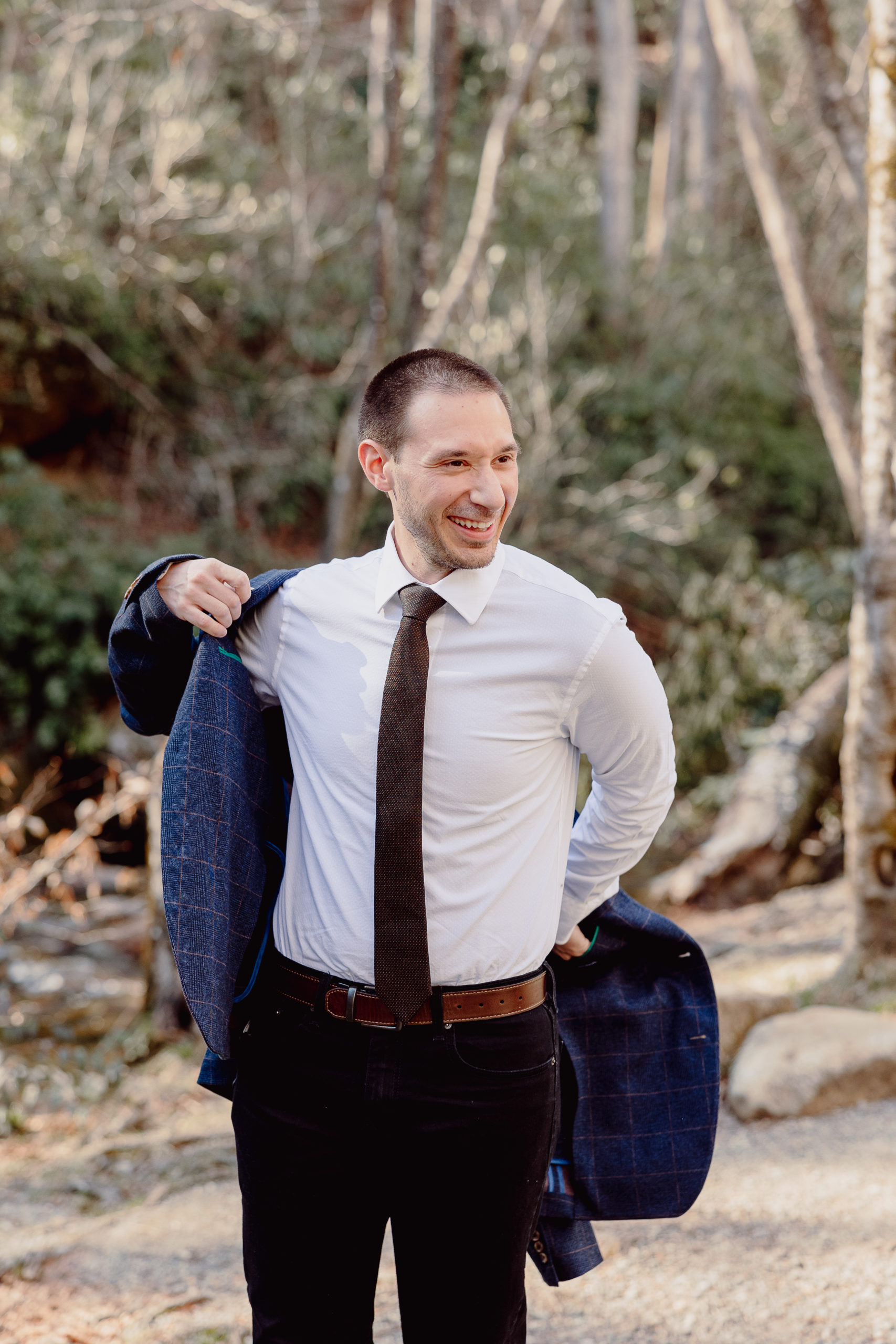 groom-puts-jacket-on-at-elopement-elope-outdoors