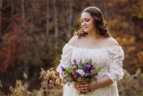 Bride posing for photo with floral arrangement after North Carolina elopement.