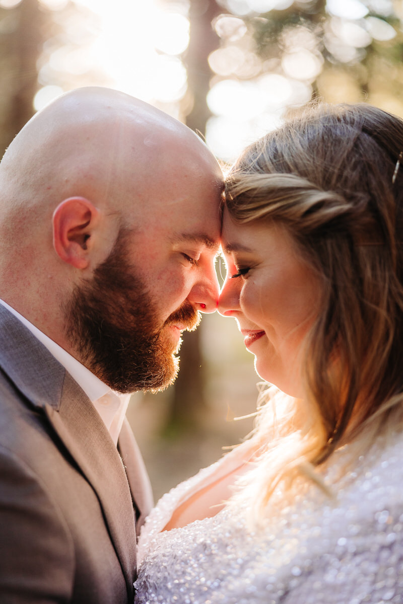 A close-up of a couple touching foreheads in soft natural light.