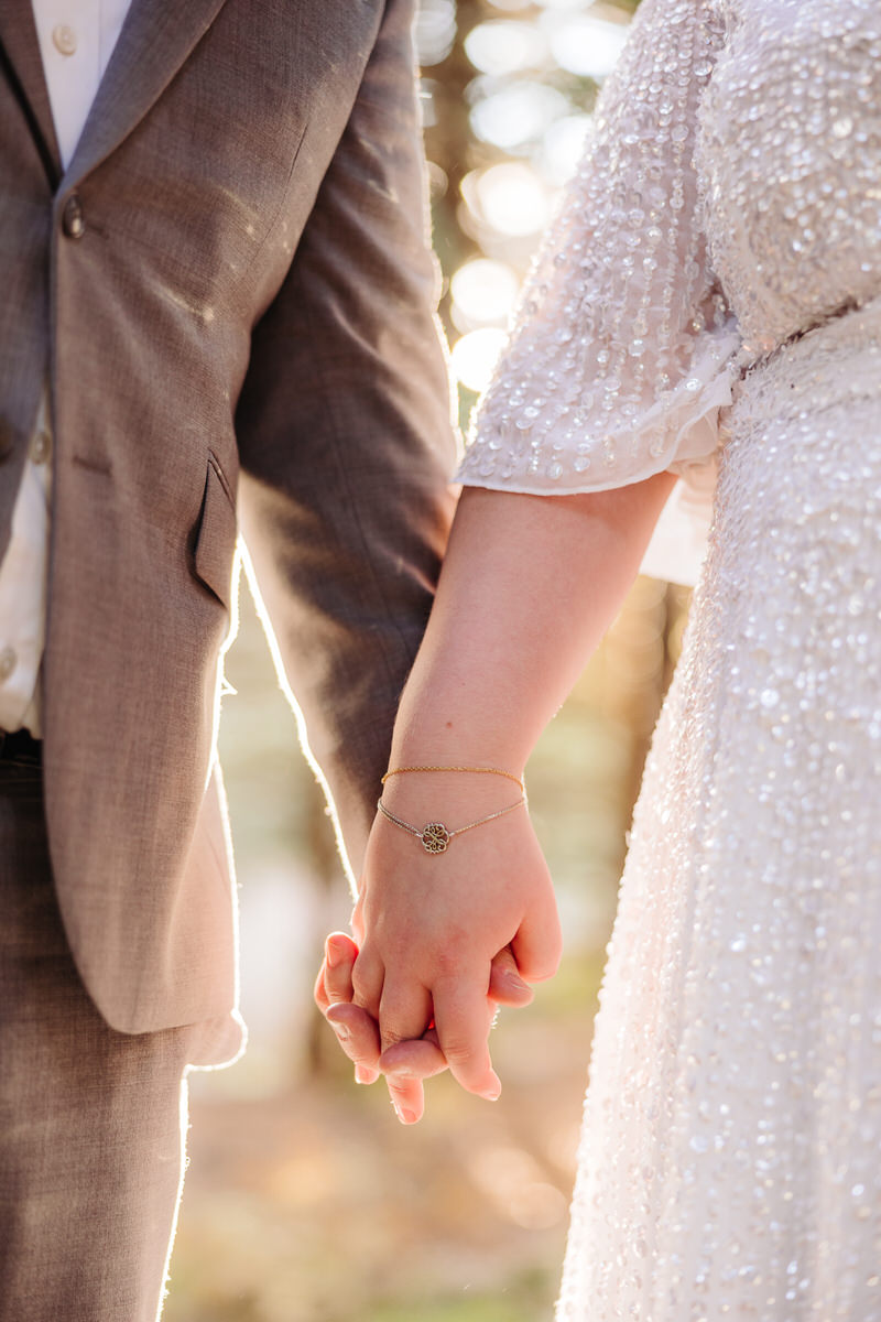 A close-up of a couple holding hands with the woman's bracelet visible.