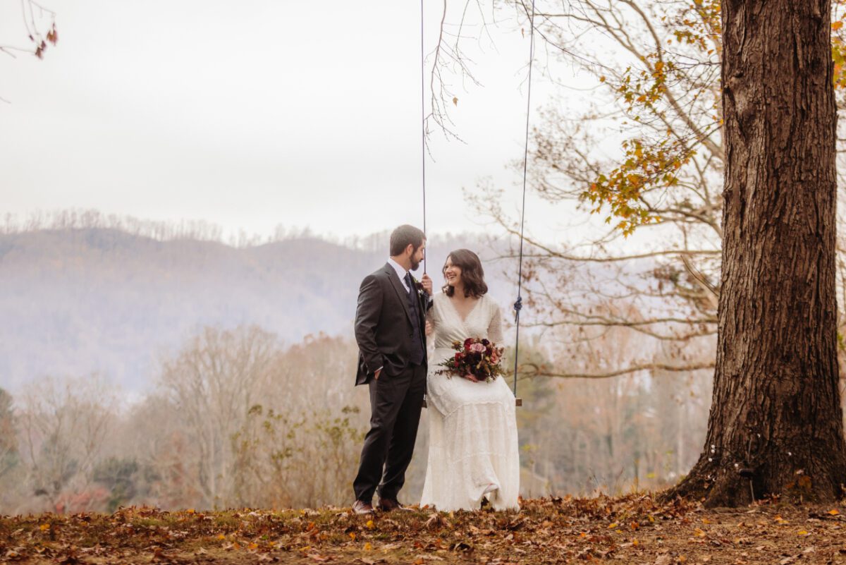 bride and groom portraits. bride is sitting on a tree swing.