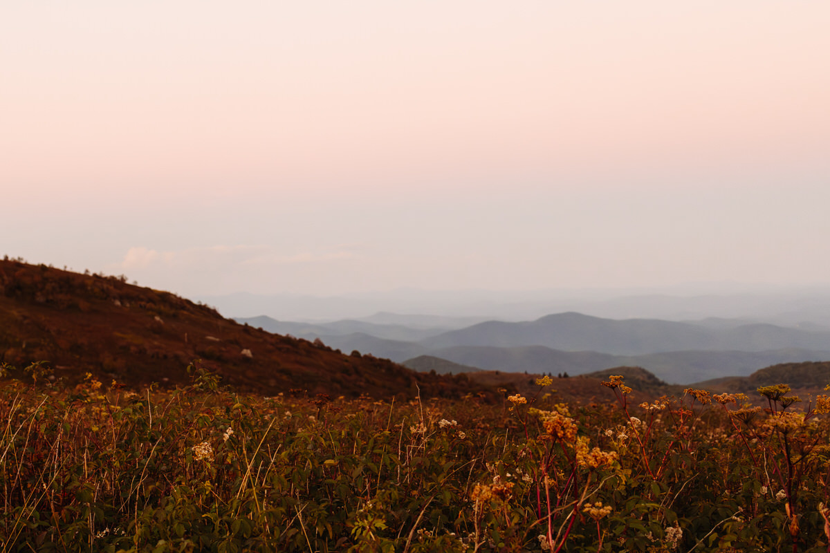 Expansive mountain landscape view from Black Balsam Knob, with rolling Blue Ridge peaks fading into the misty horizon under an open sky.