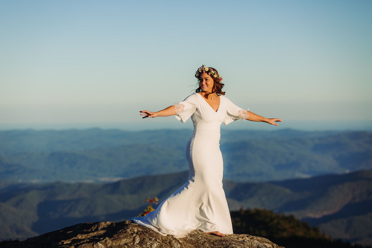 Joyful bride embracing the beauty of her outdoor elopement, radiating freedom and happiness as she explores nature in her flowing gown, surrounded by breathtaking mountain view