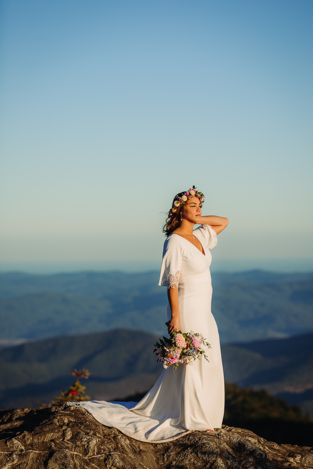 Joyful bride embracing the beauty of her outdoor elopement, radiating freedom and happiness as she explores nature in her flowing gown, surrounded by breathtaking mountain view
