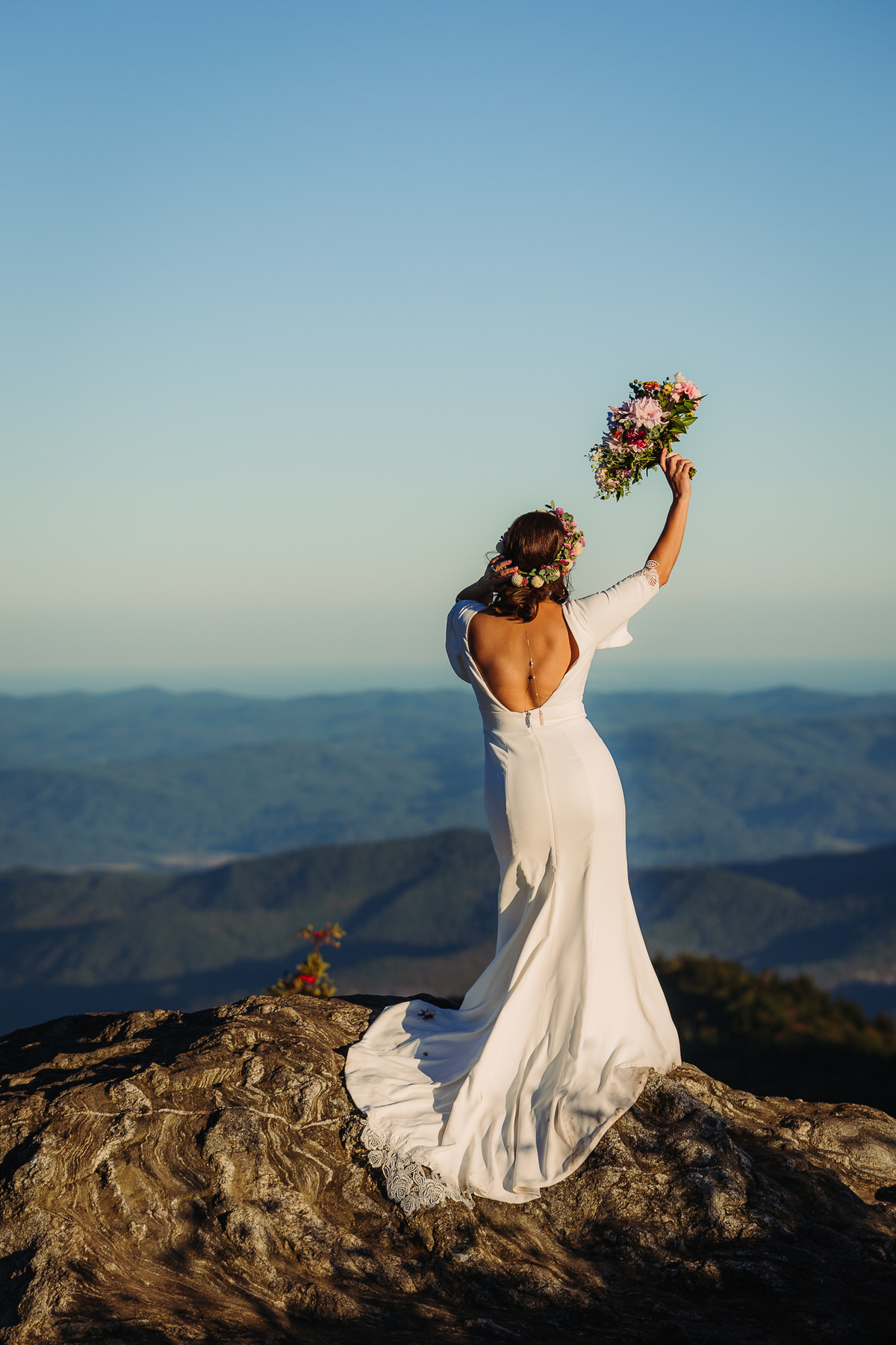 Joyful bride embracing the beauty of her outdoor elopement, radiating freedom and happiness as she explores nature in her flowing gown, surrounded by breathtaking mountain view