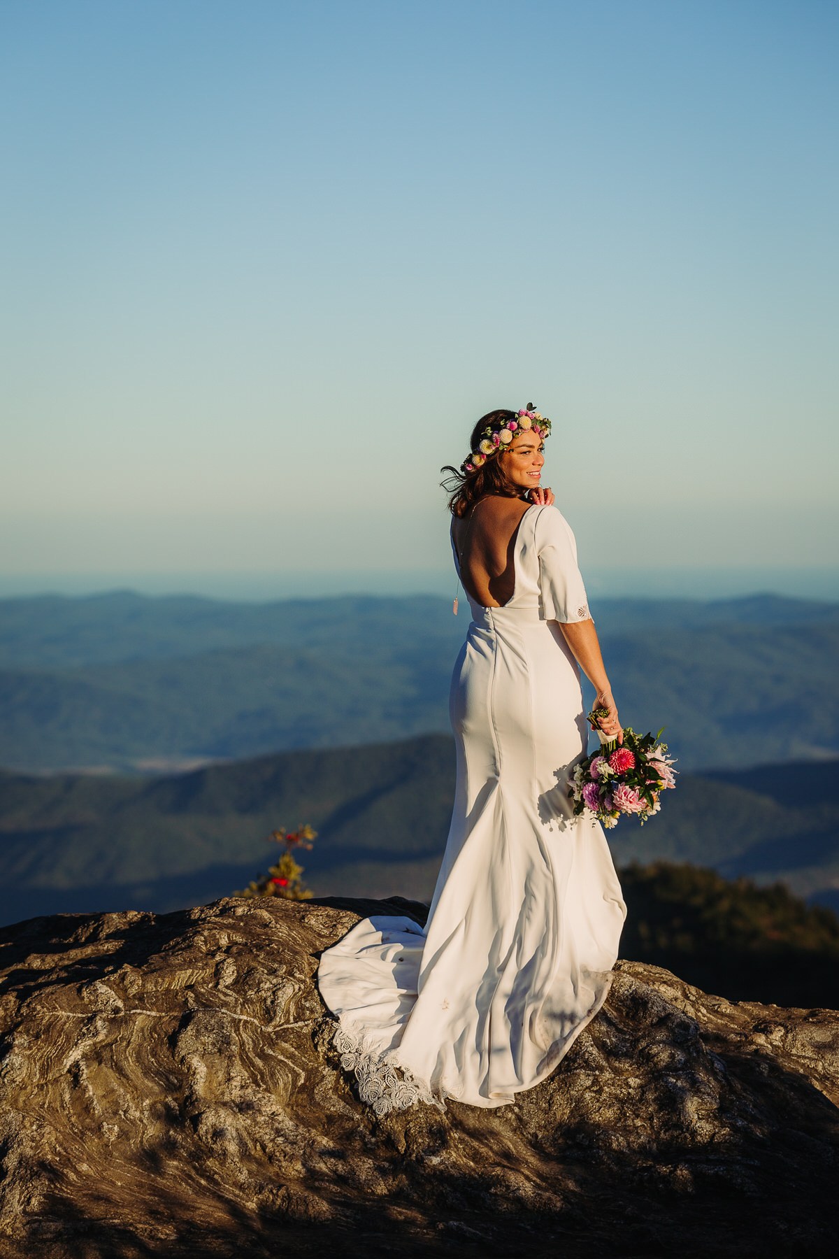 Joyful bride embracing the beauty of her outdoor elopement, radiating freedom and happiness as she explores nature in her flowing gown, surrounded by breathtaking mountain view