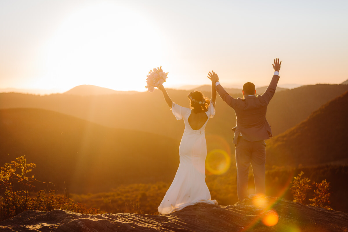 Carefree bride enjoying her intimate outdoor elopement with nature, radiating joy and freedom in a stunning mountain setting, with flowing dress and natural surroundings
