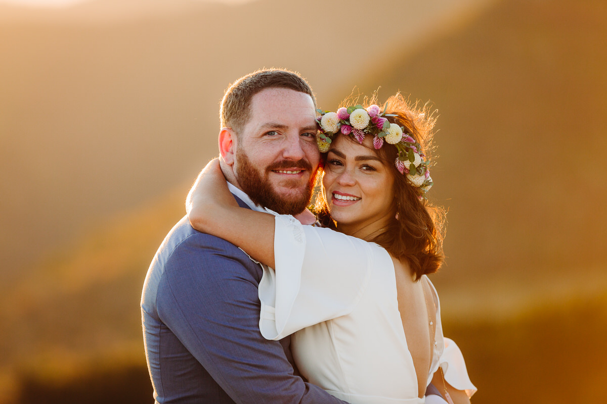Carefree bride enjoying her intimate outdoor elopement with nature, radiating joy and freedom in a stunning mountain setting, with flowing dress and natural surroundings