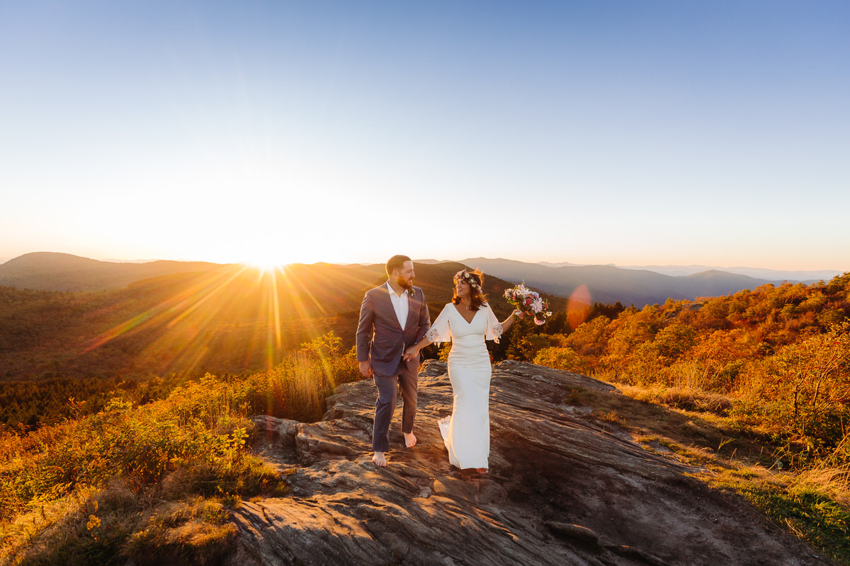 Carefree bride enjoying her intimate outdoor elopement with nature, radiating joy and freedom in a stunning mountain setting, with flowing dress and natural surroundings