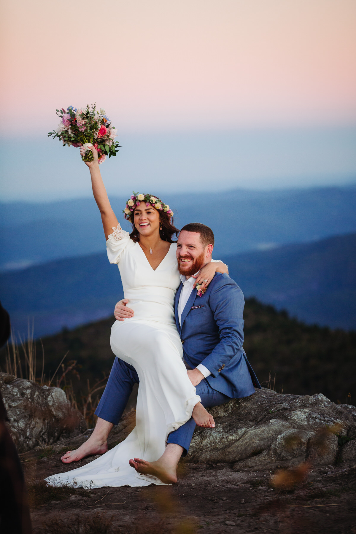 Carefree bride enjoying her intimate outdoor elopement with nature, radiating joy and freedom in a stunning mountain setting, with flowing dress and natural surroundings
