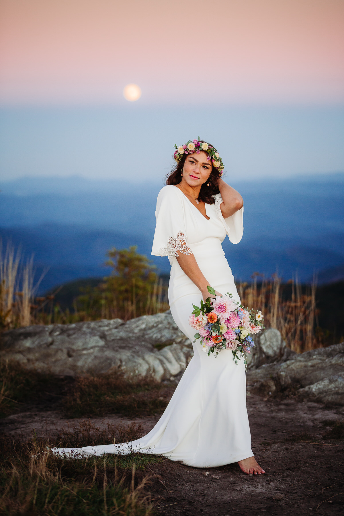 Carefree bride enjoying her intimate outdoor elopement with nature, radiating joy and freedom in a stunning mountain setting, with flowing dress and natural surroundings