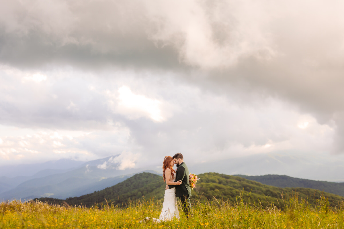 Romantic elopement couple embracing on a mountaintop at sunset in the Blue Ridge Mountains.