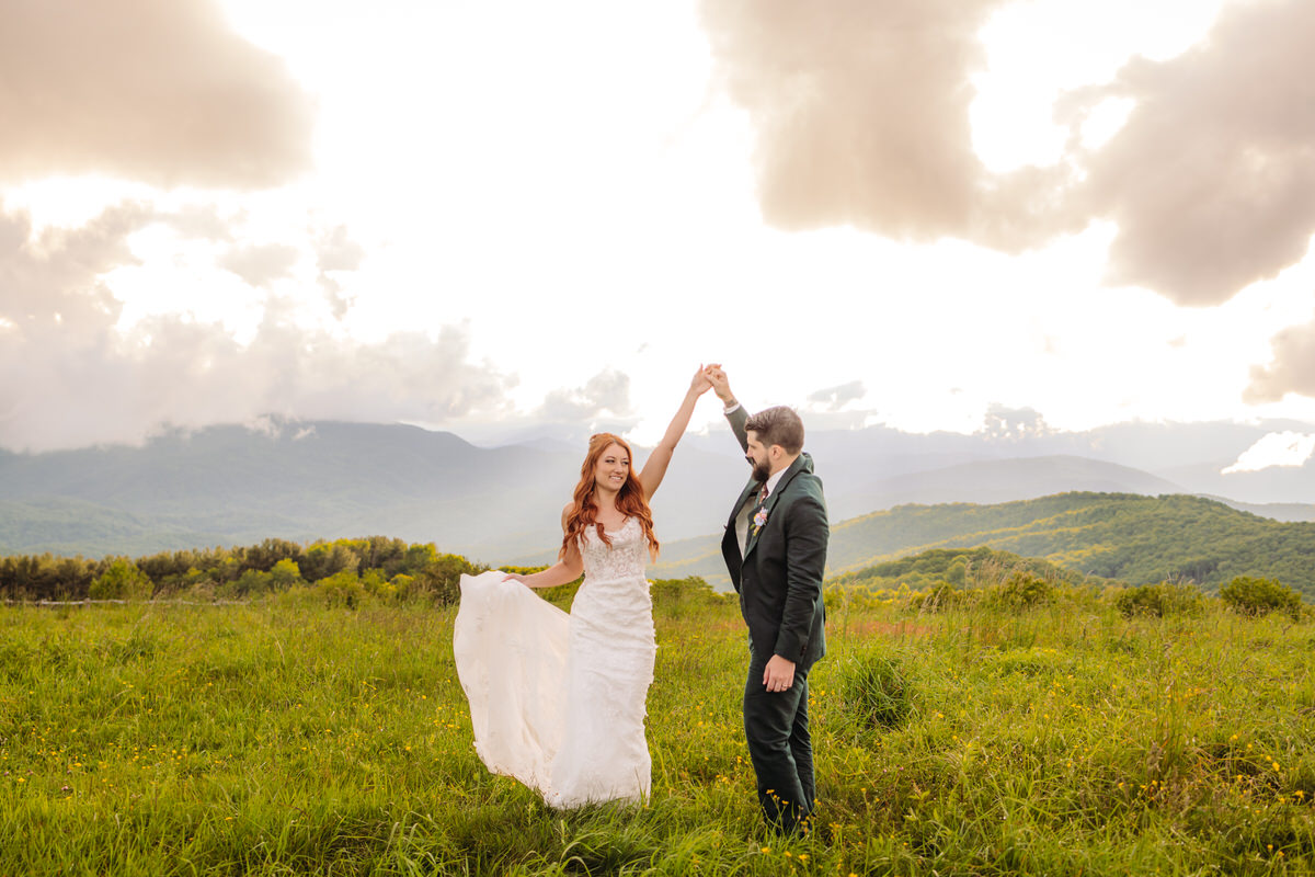 A couple dances together on a mountaintop after their elopement ceremony, with breathtaking mountain views in the background.