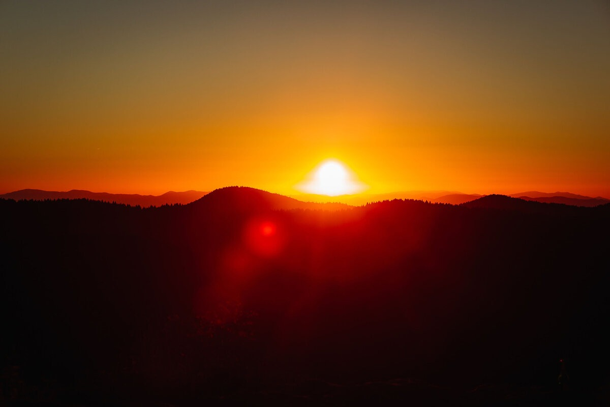 Golden sunrise over mountain peaks during a Black Balsam Knob Elopement Experience, casting warm light across the landscape.