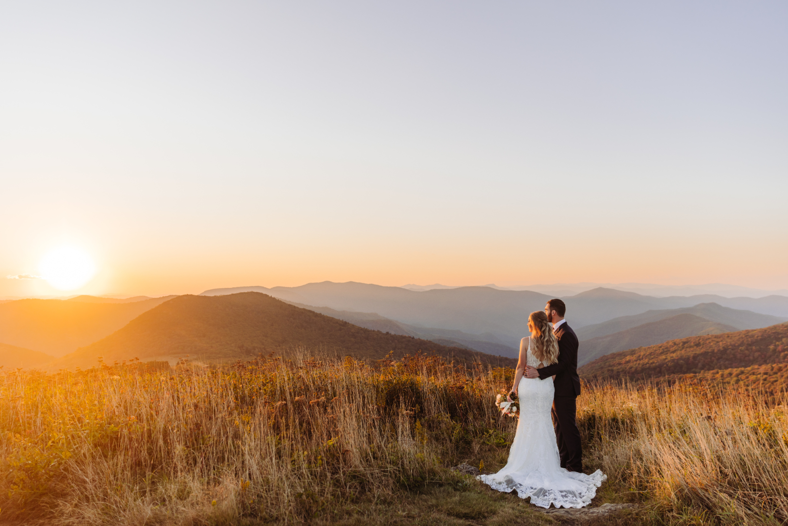 A couple stands together at sunset surrounded by golden fall foliage during their Asheville elopement.