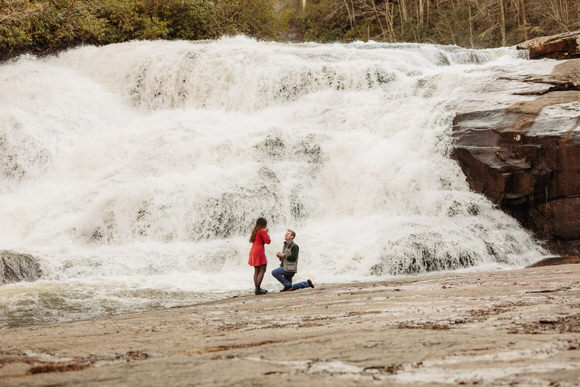 Man proposes at the base of a rushing waterfall.