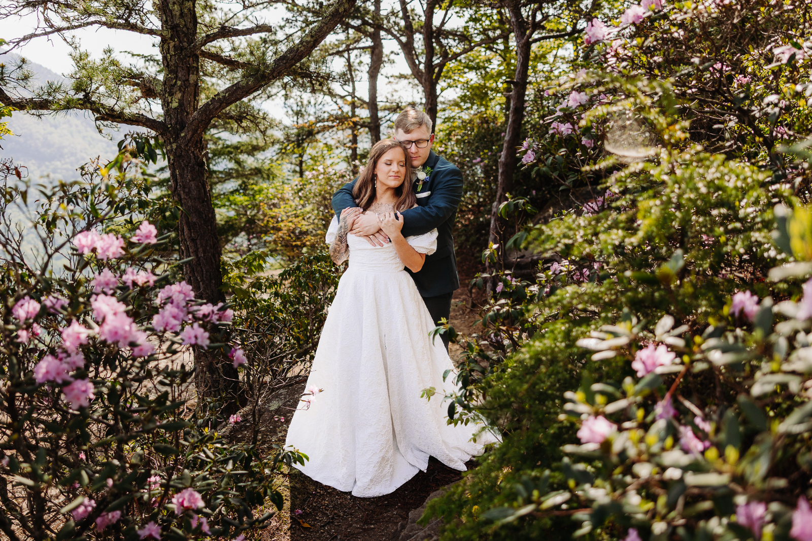 Surrounded by blooming rhododendrons, a couple embraces during their spring Asheville elopement.