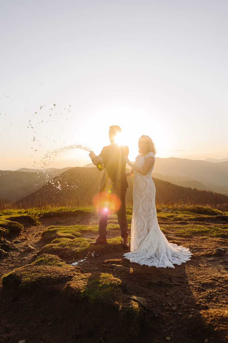 couple on their elopement day with a foaming bottle of champagne during their sunset ceremony