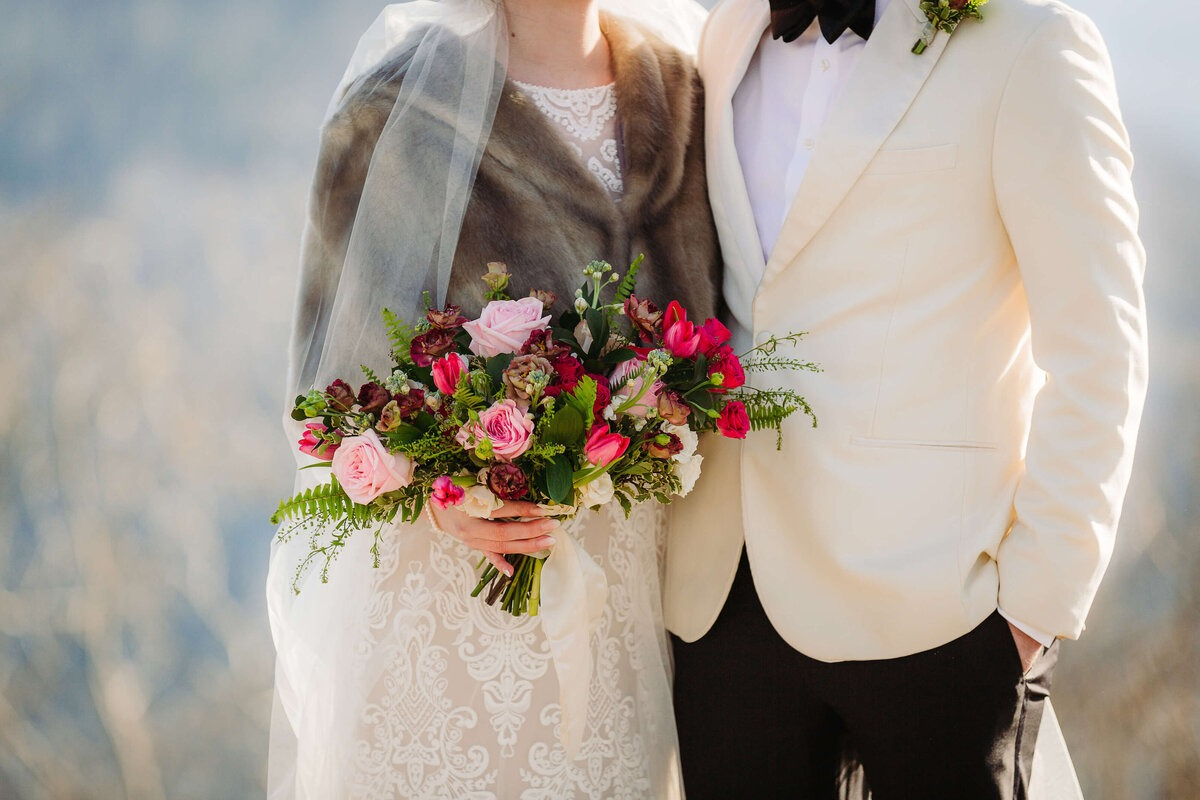 Bride and groom holding vibrant bouquet, styled by our Vendor Dream Team for an Asheville mountain elopement.