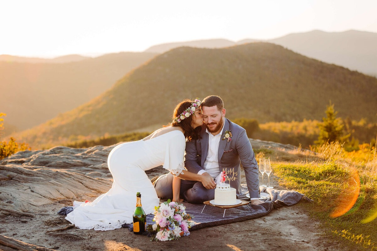 Couple cutting cake during mountain sunset picnic, captured by our Vendor Dream Team in Asheville.