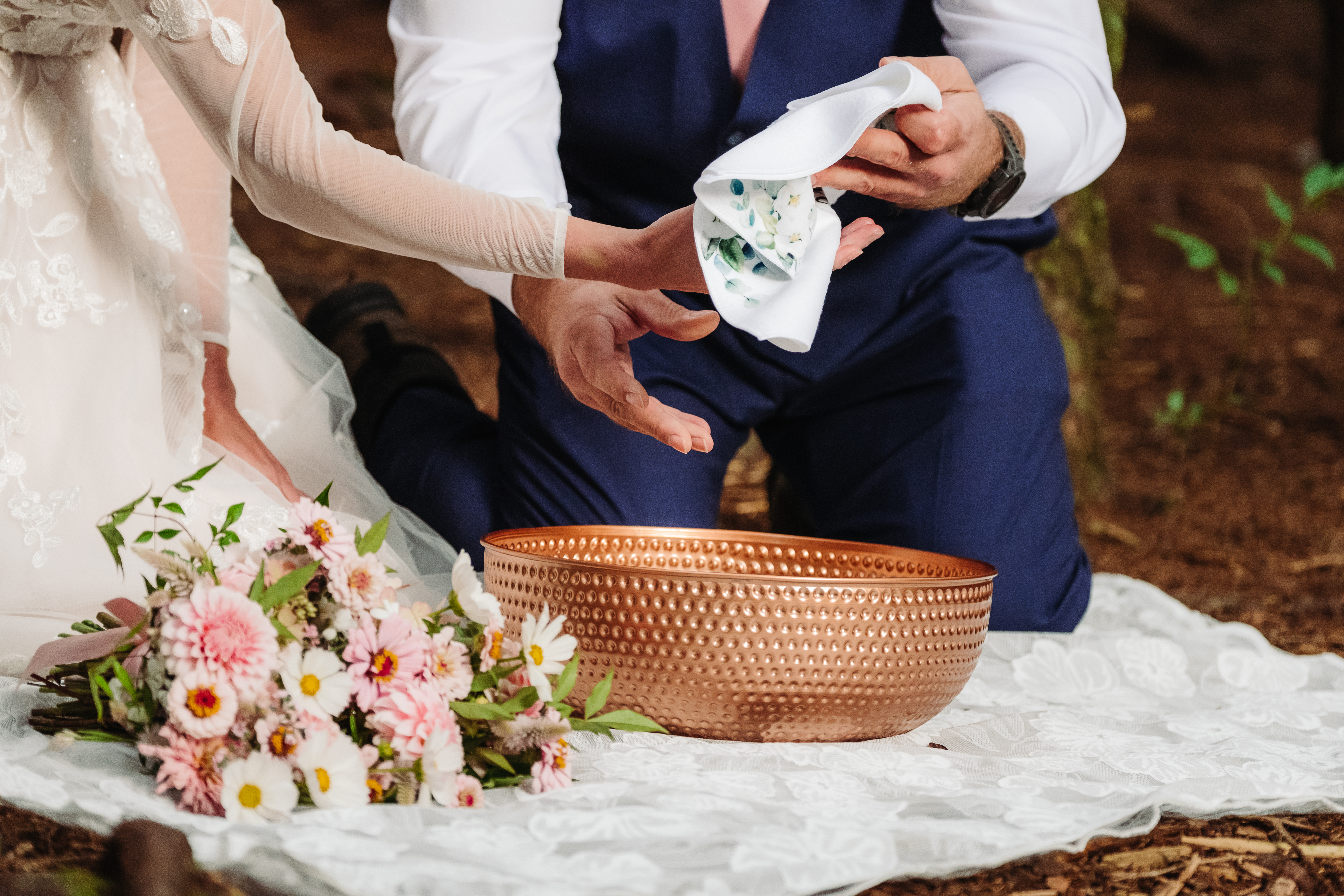 Couple performs symbolic handwashing ritual with copper bowl and flowers, a way to incorporate personal touches into your elopement.
