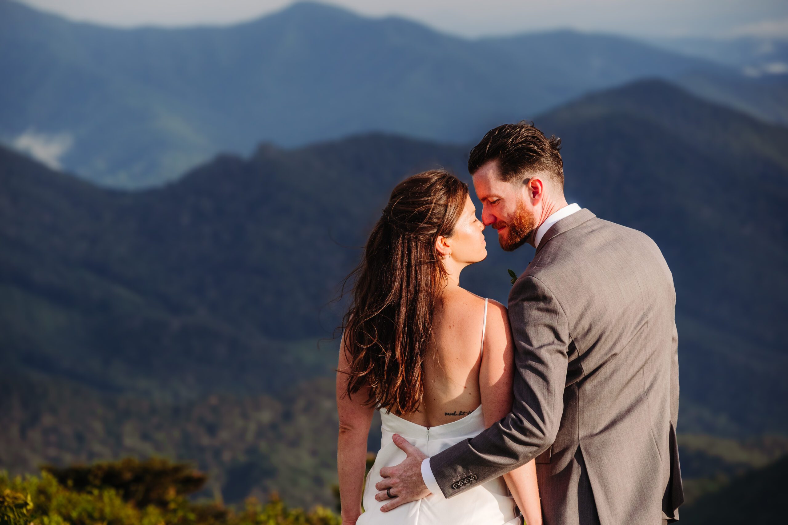 Bride and groom share an intimate moment on a mountaintop with sweeping blue ridge views.