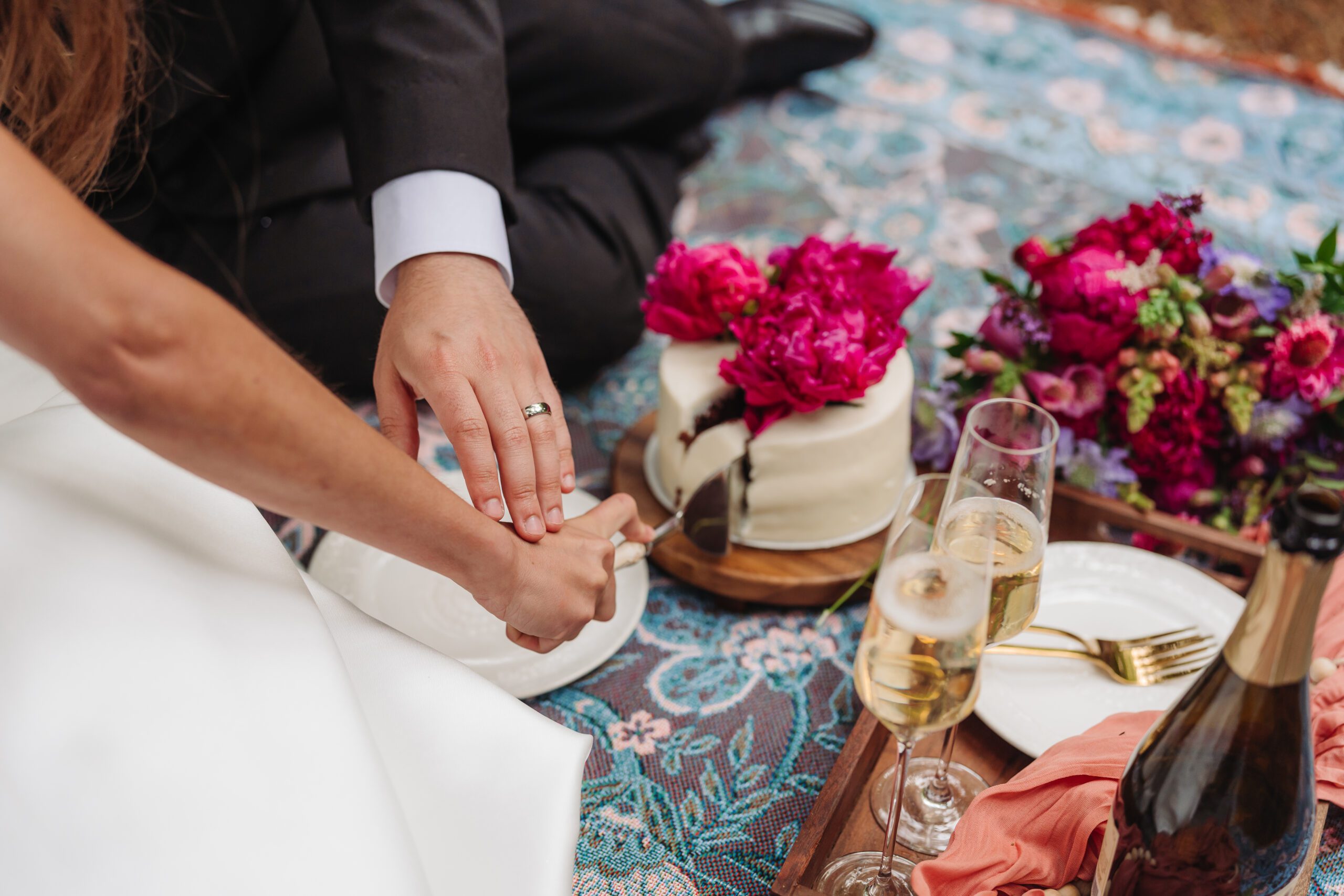 Couple cuts wedding cake during a picnic celebration, a sweet part of their post-elopement adventures.