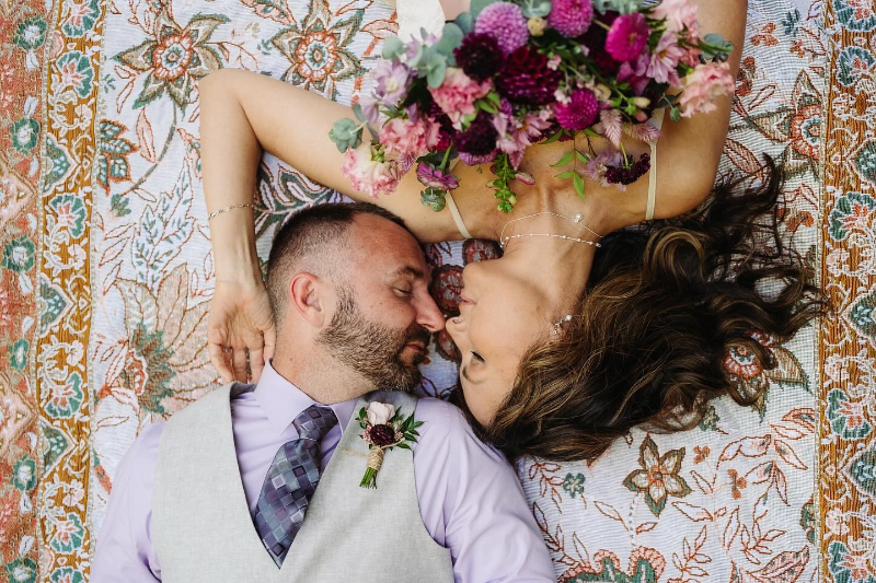 Couple lying on a patterned blanket, sharing an intimate moment during their day-after wedding photo session.