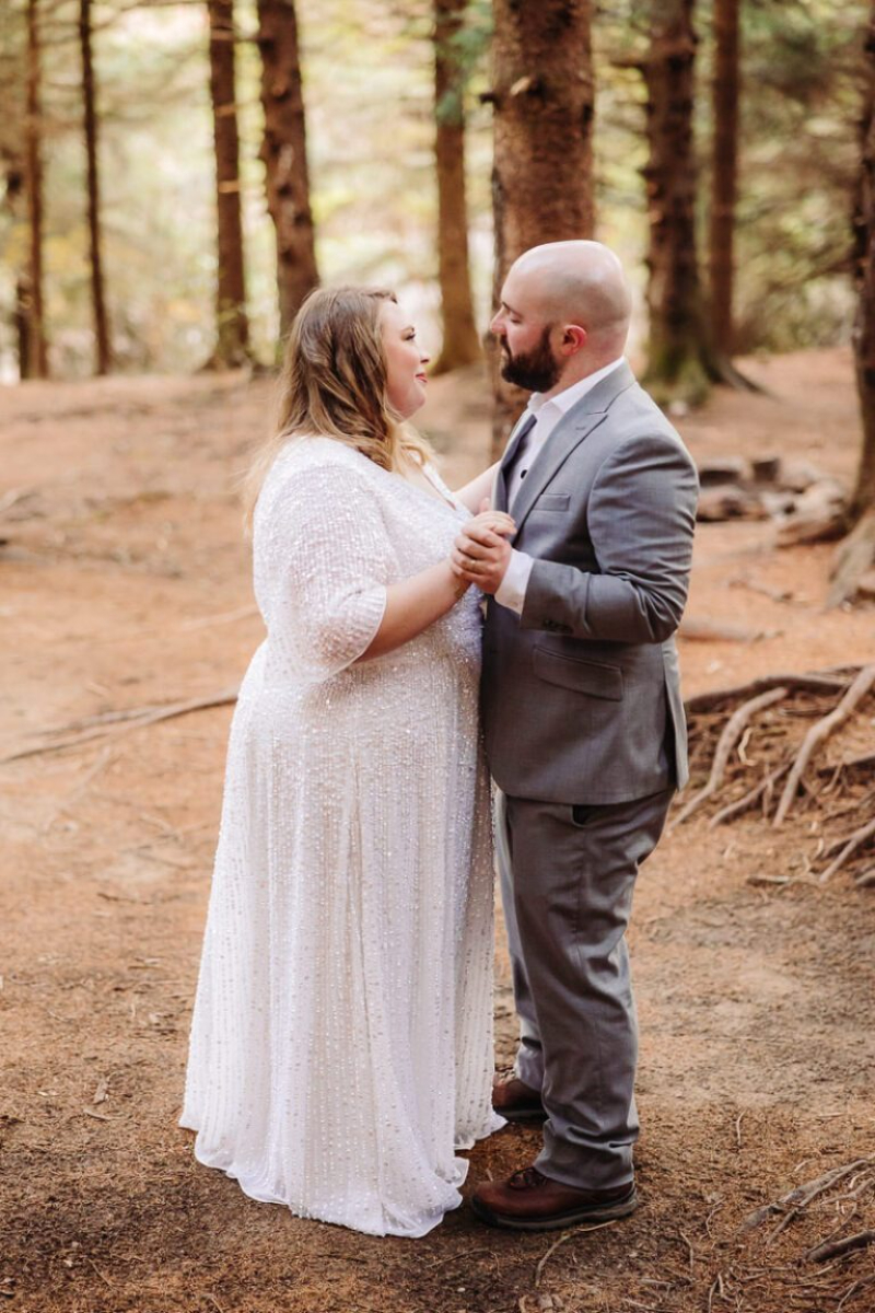 Couple holds hands and smiles while renewing their vows in a quiet forest near Asheville.