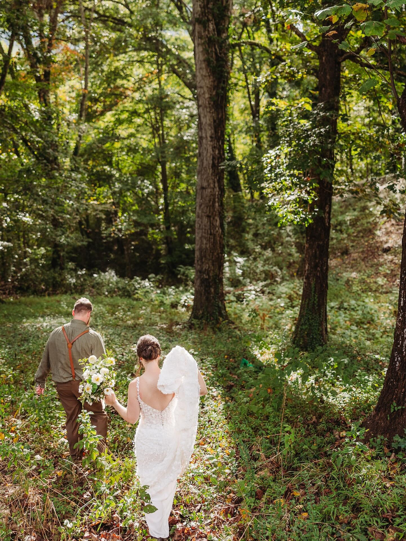 Bride and groom walking through lush greenery at a secret forest elopement locations in Asheville.