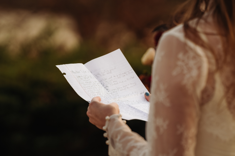 A bride reads handwritten vows outdoors, reflecting what to expect the week of your elopement.