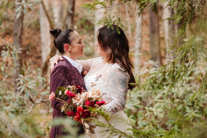 Two brides share a quiet forest moment, showing you never need to justify your elopement choice.