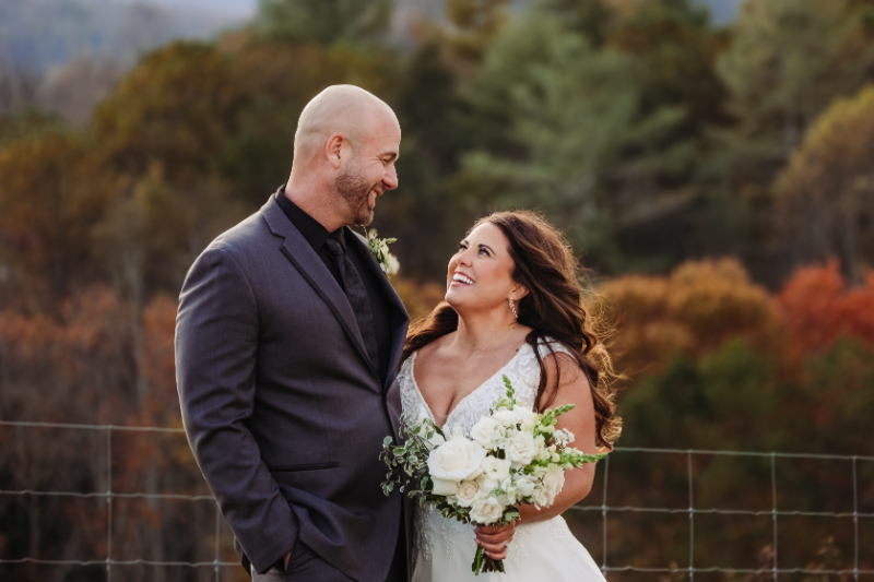 Couple smiling after vows, holding flowers outdoors—no need to justify your elopement in nature.