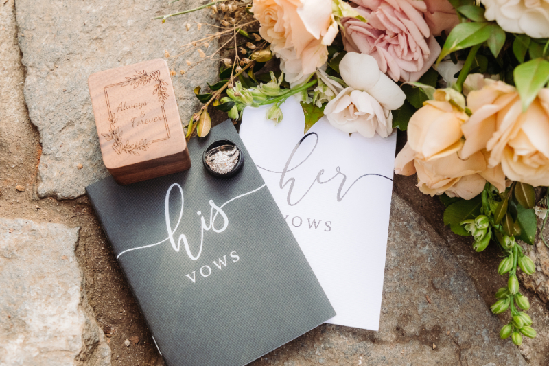 Floral flat lay with vow books and rings, a reminder you don’t need to justify your elopement.