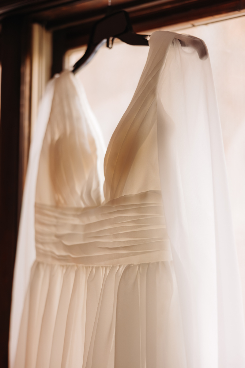 Simple bridal gown hanging in window light, perfect for intimate weekday elopements in the mountains.