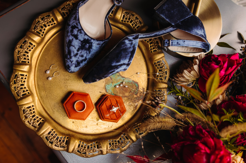 Flat lay of velvet shoes, rings, and florals styled for weekday elopements in the mountains.