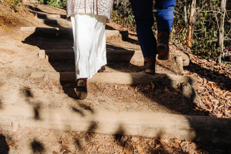 Couple walking up forest trail in wedding attire, following Leave No Trace principles during elopement.