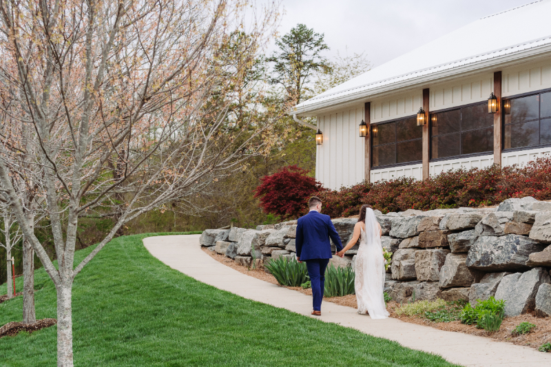 Couple walking hand in hand at Blue Ridge Mountain Wedding Venues with scenic cabin backdrop.