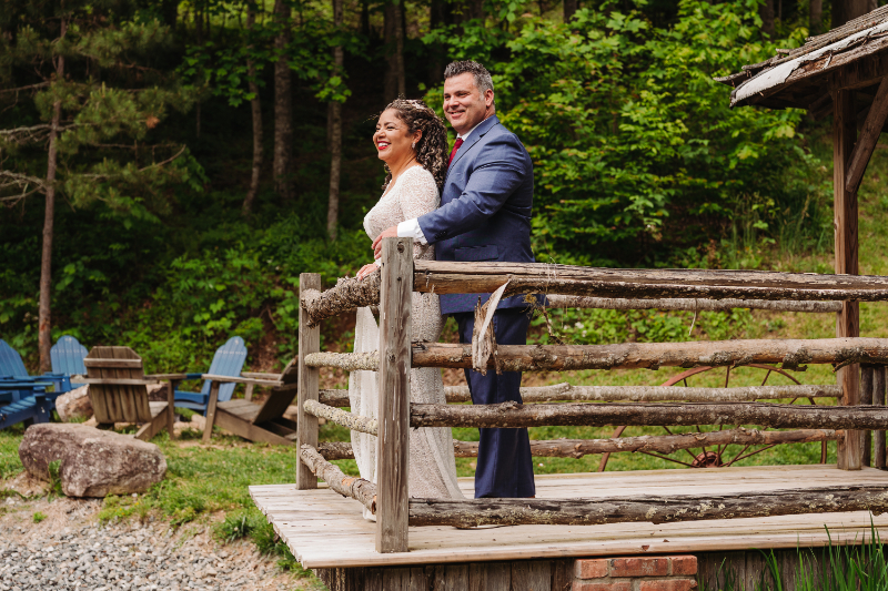 Bride and groom smiling on rustic wooden deck surrounded by lush forest at a Blue Ridge Mountain Venues