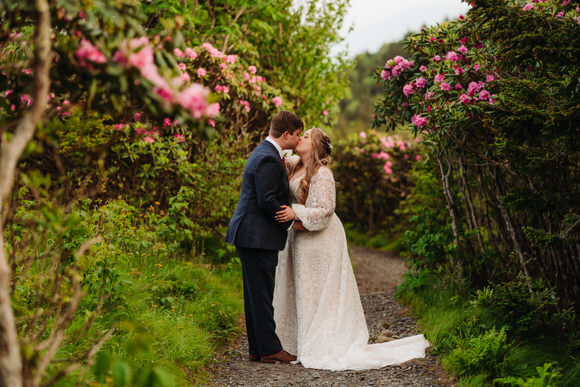 Intimate elopement kiss surrounded by blooming rhododendrons in the Blue Ridge Mountains
