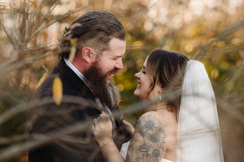 Couple smiling together during a romantic elopement in Asheville NC, surrounded by warm forest light and fall leaves.