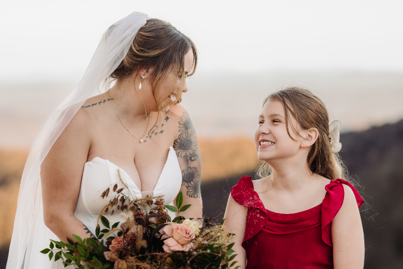 Bride smiling at a young girl during a mountain overlook elopement in Asheville NC at sunset.