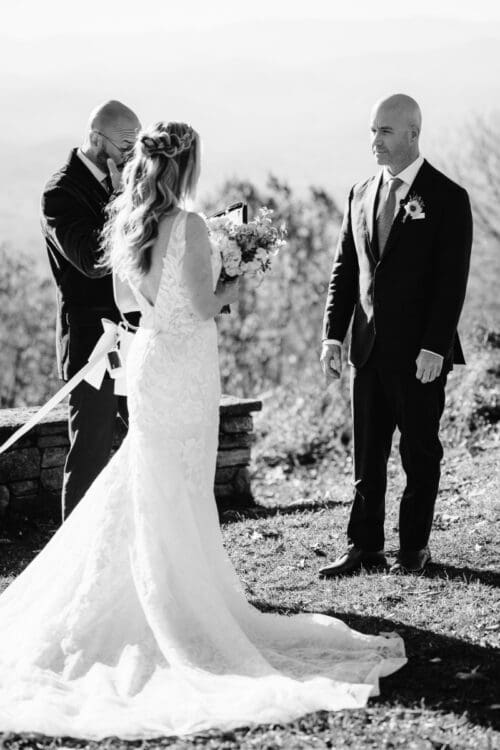 Black and white photo of couple holding hands, walking together after ceremony