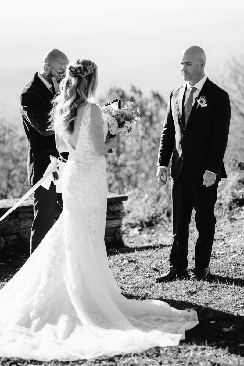 Black and white photo of couple holding hands, walking together after ceremony