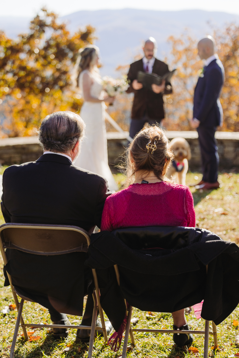 Guests seated and watching ceremony, framed by warm fall colors and mountain views