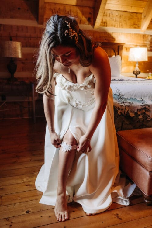 Bride adjusting dress in warm cabin light, cozy places to elope in Asheville NC