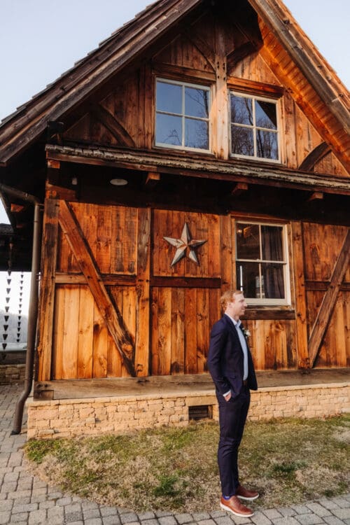 Groom standing outside rustic cabin venue, classic places to elope in Asheville NC