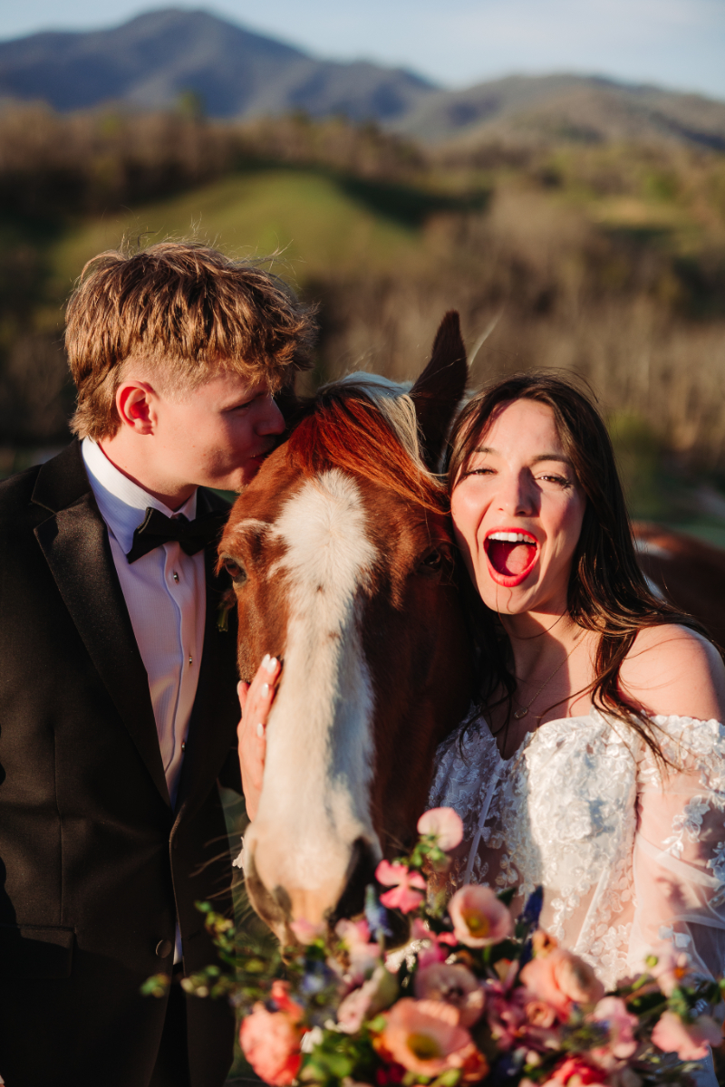Couple laughs beside a horse, sharing a joyful and playful moment outdoors